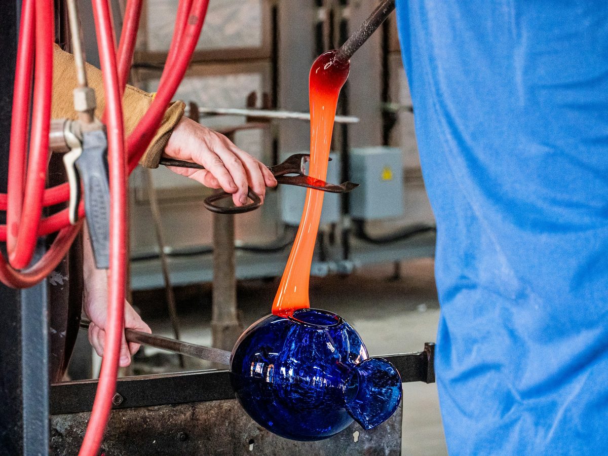 A glassblower shaping hot glass by hand